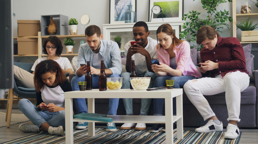 People looking at their phones on a couch