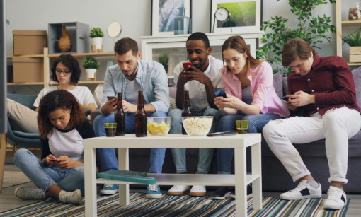 People looking at their phones on a couch